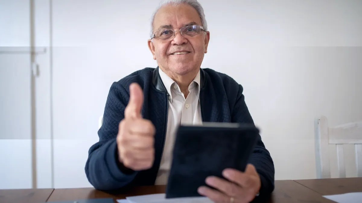 Mann mit Tablet zeigt Daumen hoch als positives Signal bei der Suche nach einer Hausverwaltung