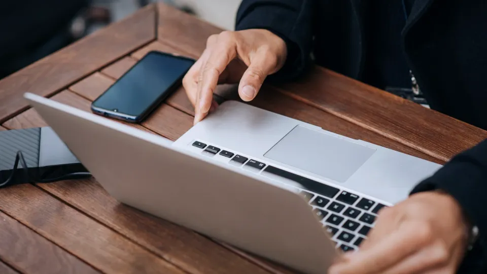 Manager arbeitet mit Laptop und Smartphone in einem Straßencafe